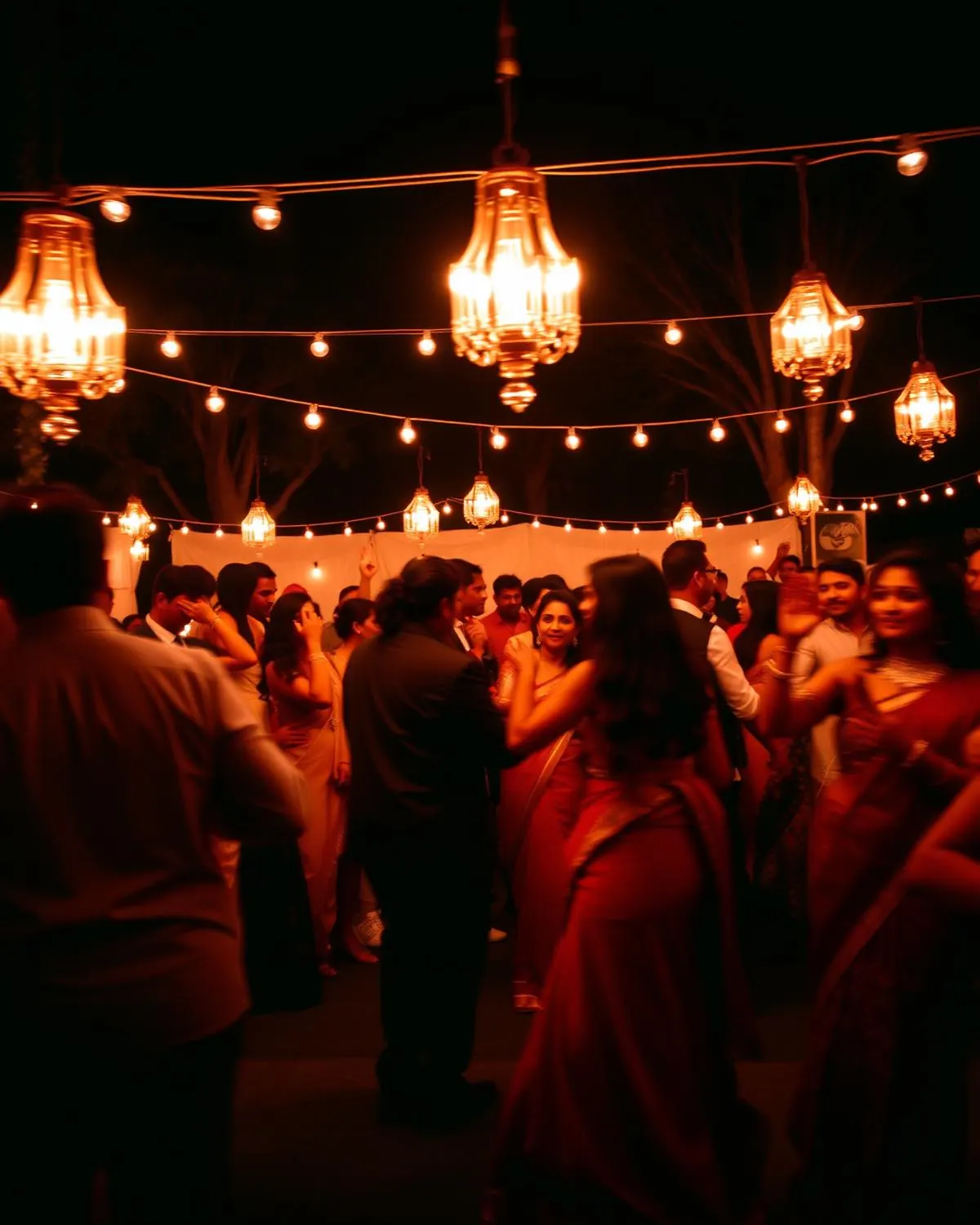 Guests dancing under warm hanging lanterns at a night reception